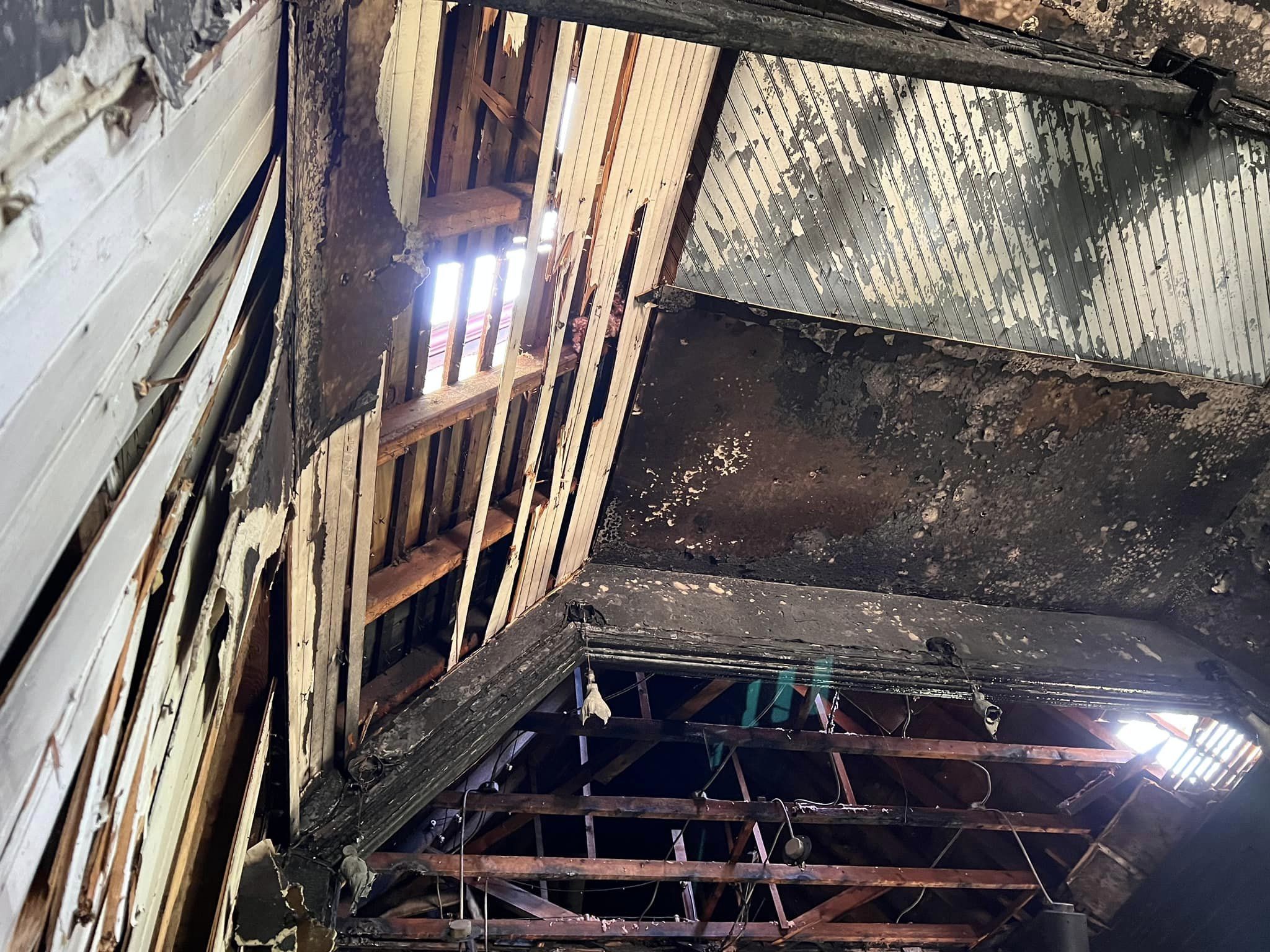 The ceiling of the Church of the Messiah, damaged by fire. Daylight shines through beams in the ceiling.