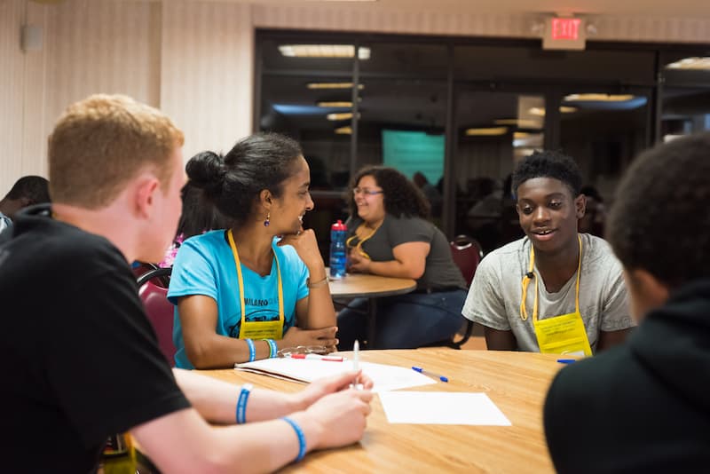 Youth gathered around a table having a discussion