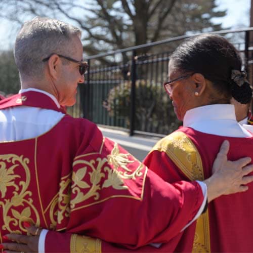 Two clergy locking arms in support