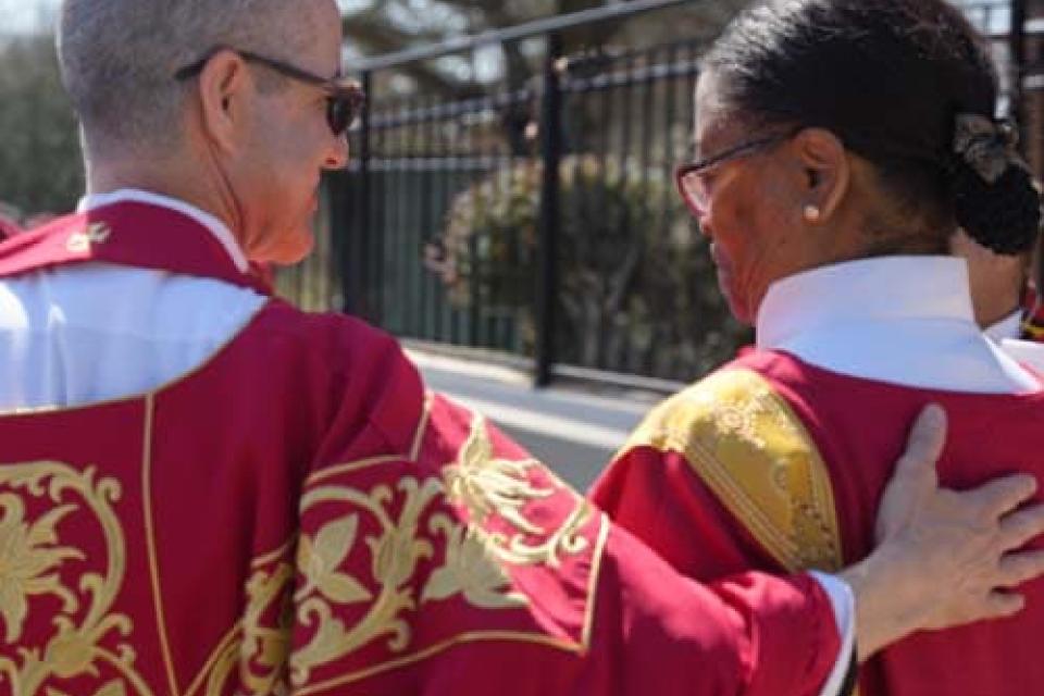 Two clergy locking arms in support