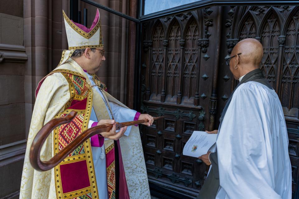 Bishop Shoemaker bangs on the front doors of the Cathedral